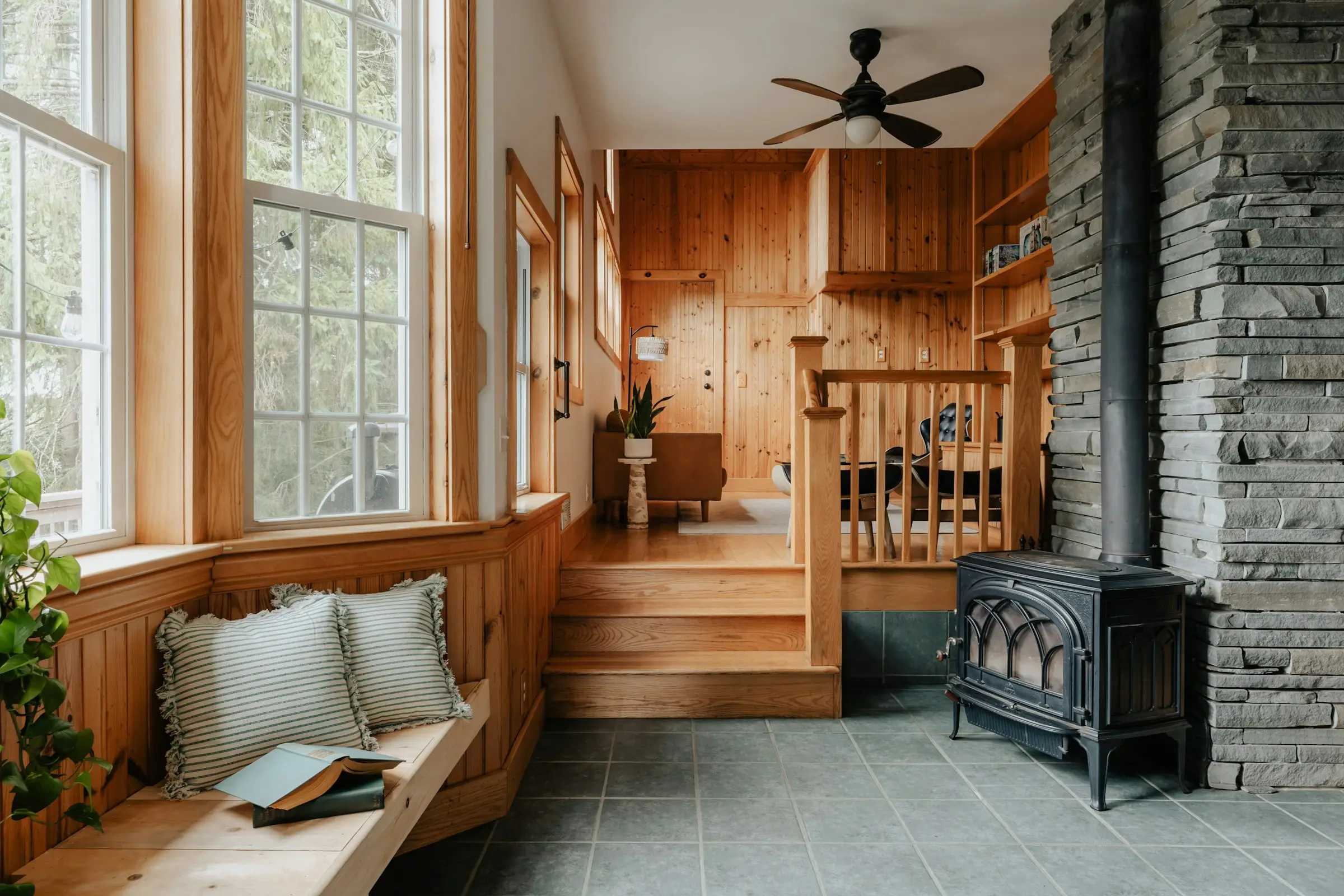 A sunlit window bench with an open book in a warm, wood-paneled room