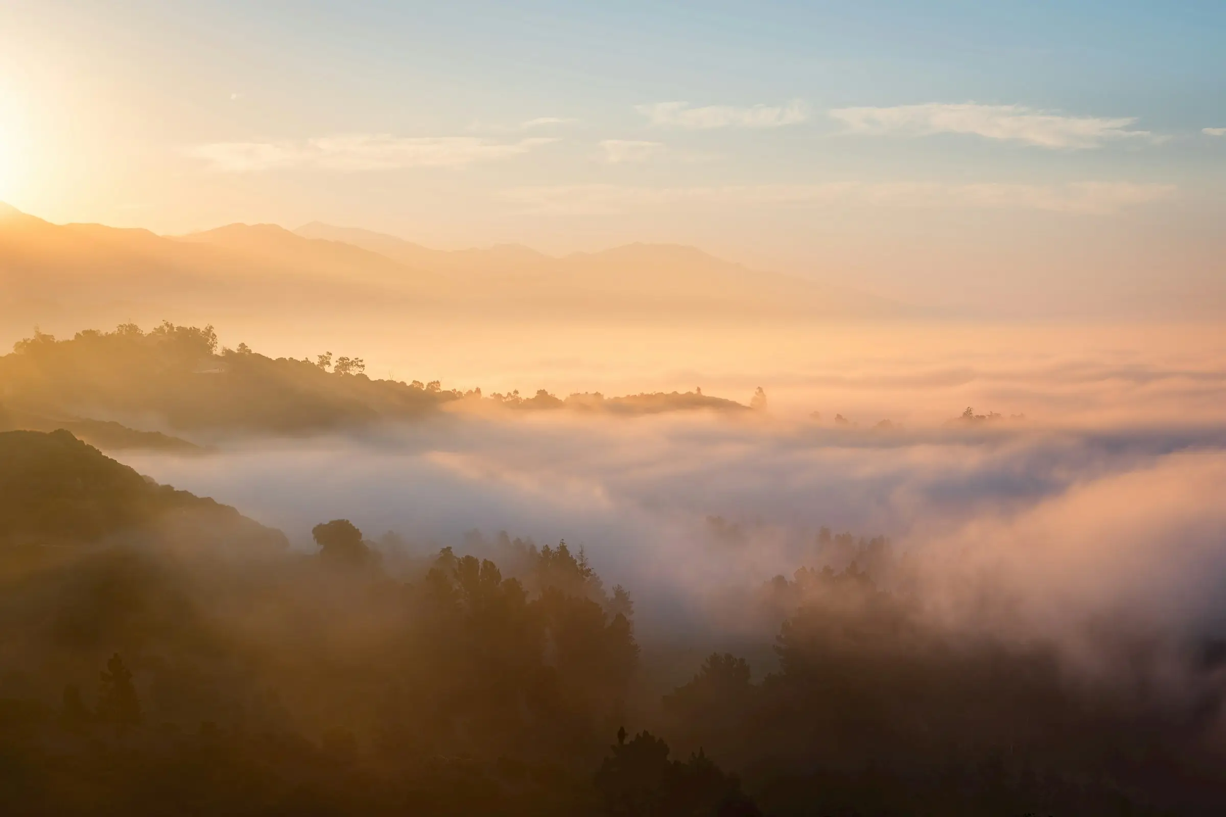 Soft mist over warm mountain ridges at golden hour