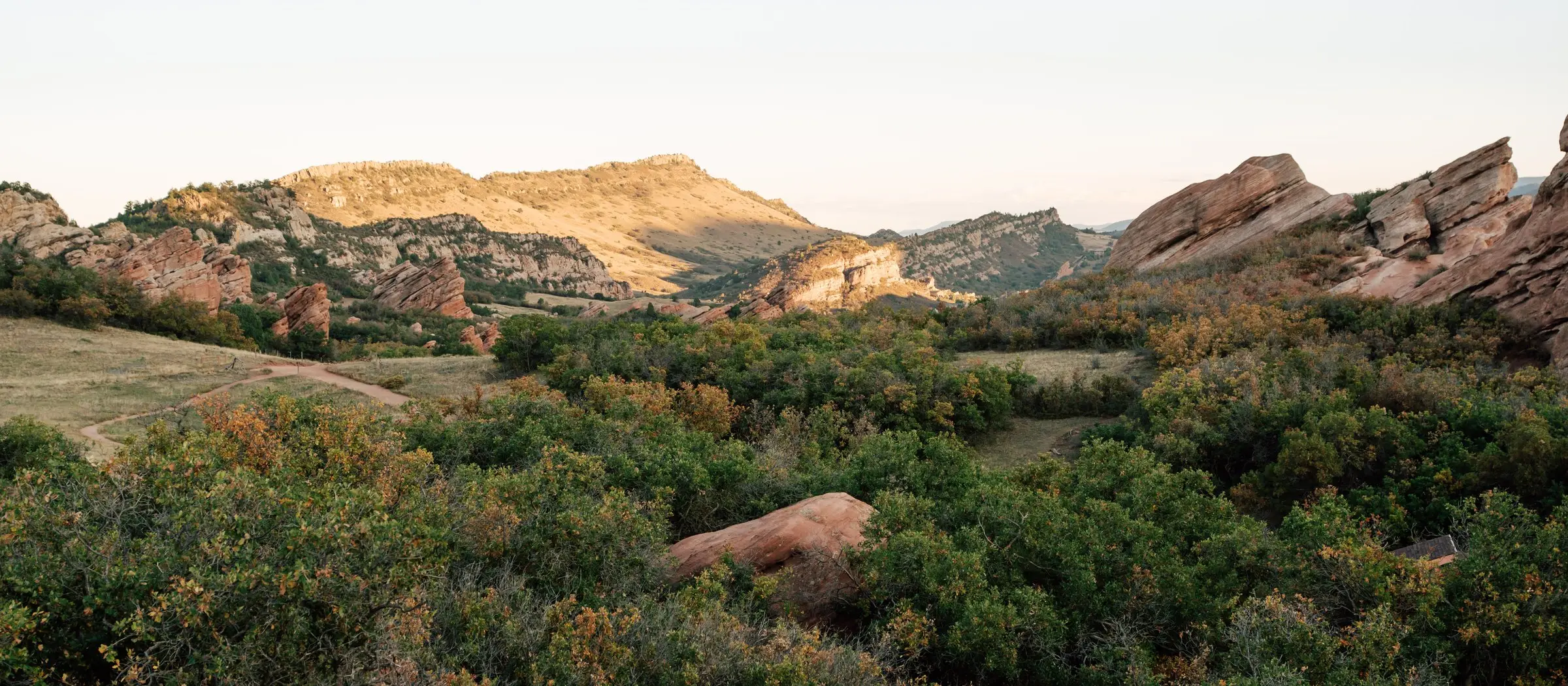 Red rock formations below a sunlit ridge in the Colorado foothills