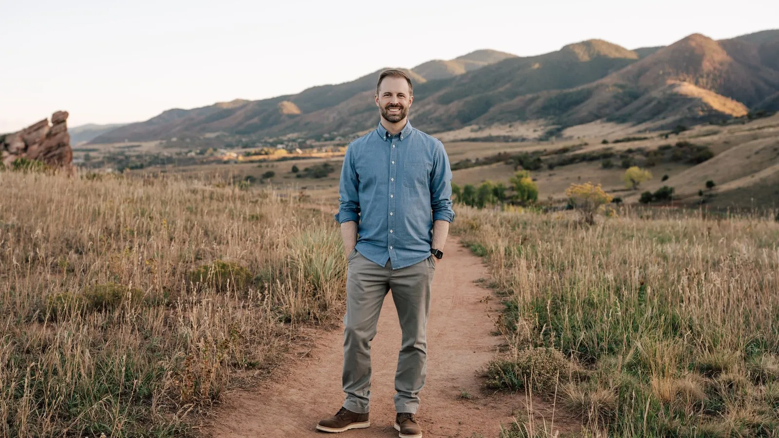 Tyler Marshall standing on a dirt trail in the Colorado foothills, smiling