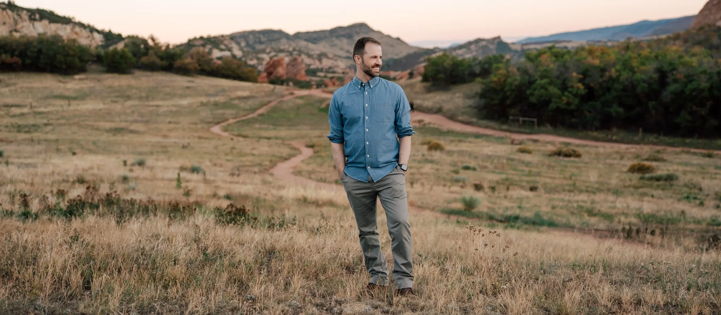Tyler Marshall standing in a foothills meadow, looking off to the side