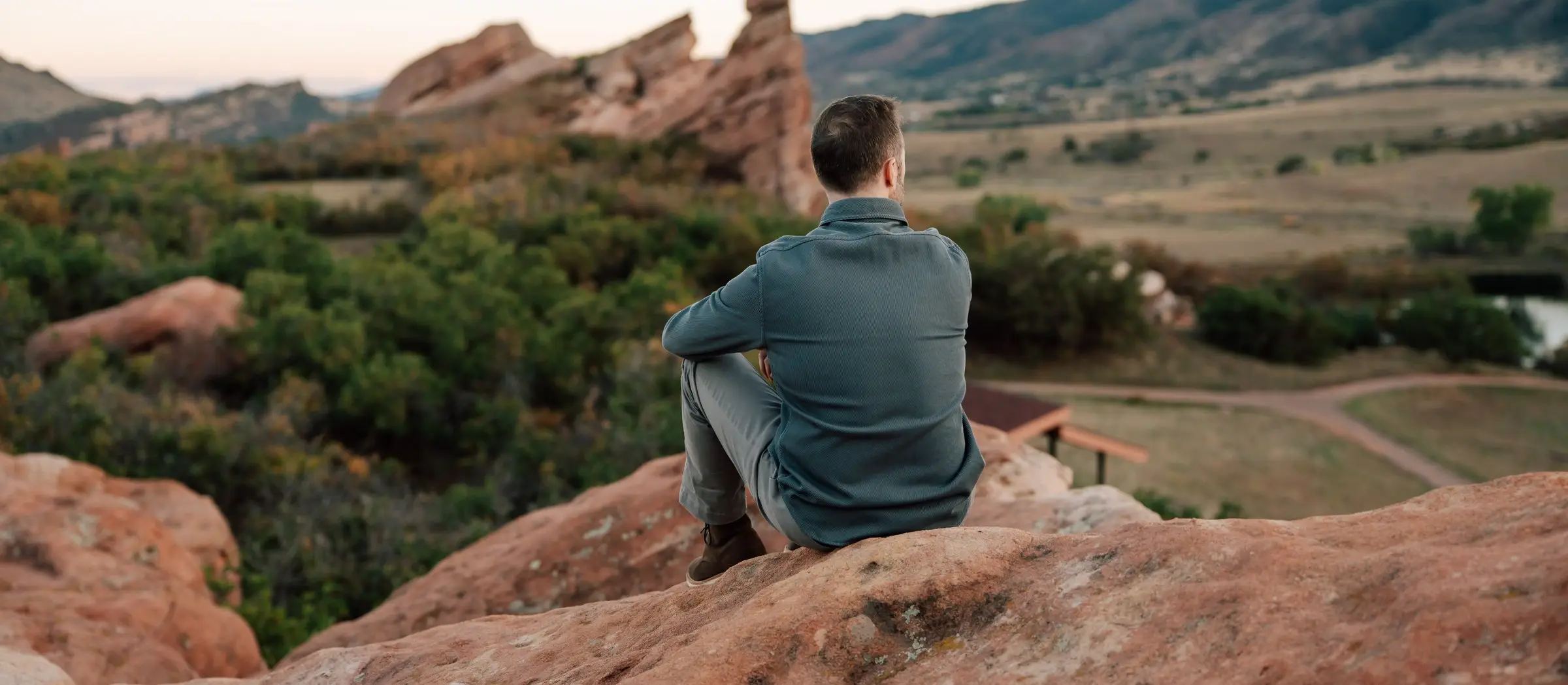 Tyler Marshall sitting on red rock, looking out over a foothills valley