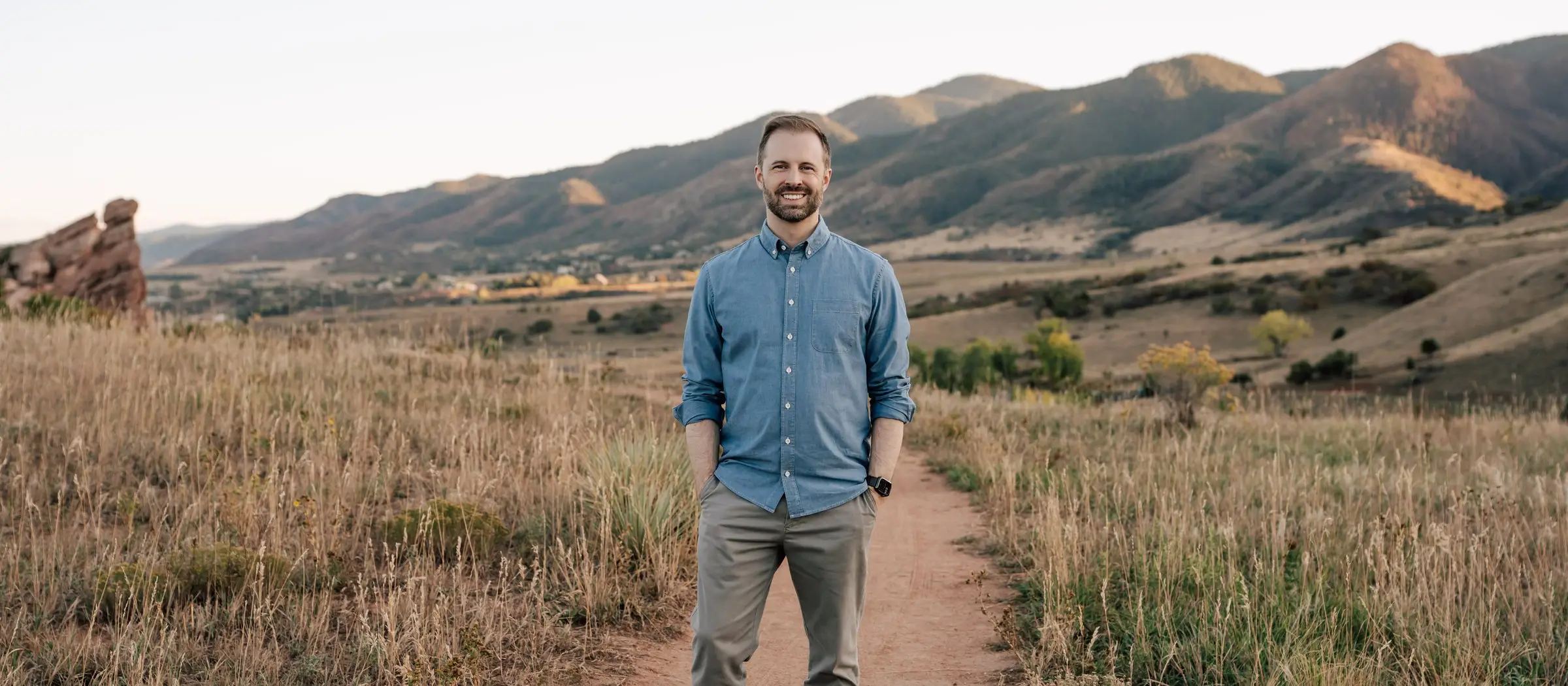 Tyler Marshall standing on a trail in the Colorado foothills, smiling